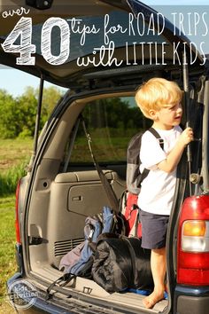 a young boy standing in the back of a truck with luggage on it's trunk