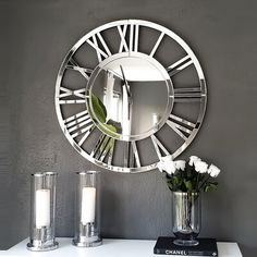 a white table topped with a vase filled with flowers next to a mirror on the wall