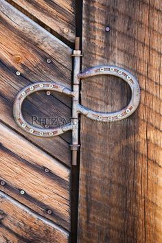 an old pair of scissors is on the side of a wooden door with rivets