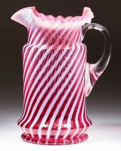 a red and white striped glass pitcher sitting on top of a table