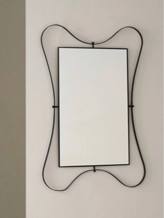 a mirror hanging on the wall with an iron frame and black metal wire around it