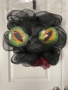 an eyeball wreath hanging on the front door with mesh netting around it's eyes