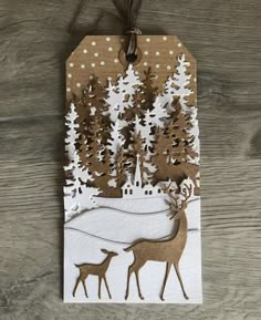 a christmas card with deer and snow scene on it, hanging from a wooden table