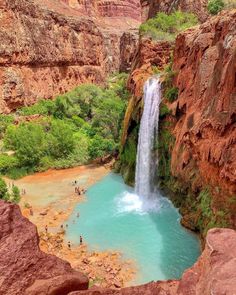 a waterfall in the middle of a canyon with blue water flowing down it's sides