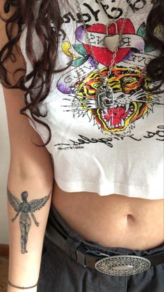 a woman with a tattoo on her arm and chest is standing in front of a wall