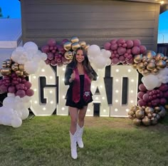 a woman standing in front of a giant balloon arch that says grand with balloons all around it