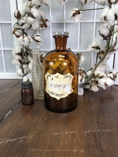 a brown glass bottle sitting on top of a wooden table next to cotton floss