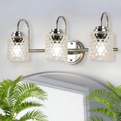 three light bathroom fixture with clear glass shades and chrome finish, on a white wall