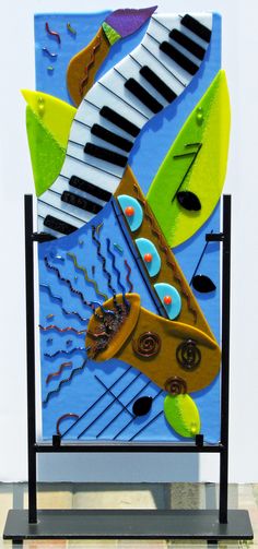 an art piece with musical instruments and music notes painted on it's sides, in front of a white wall