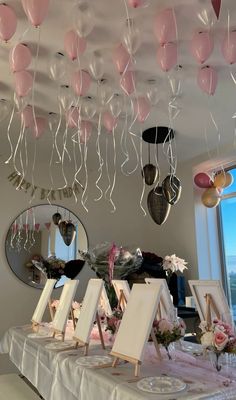 balloons are hanging from the ceiling above a table with pictures on it and flowers in vases