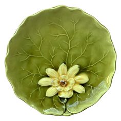 a green plate with a yellow flower in the center and leaves on it's side