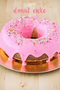 a pink frosted donut sitting on top of a gold plate