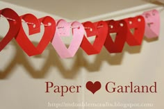 paper hearts are hanging on a string with the word paper garland written below them in red and pink