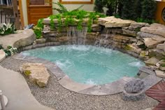 a small pool surrounded by rocks and water features a waterfall