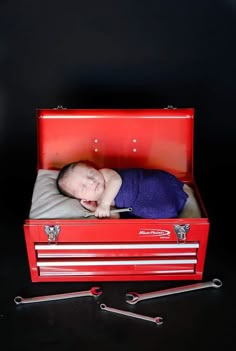 a baby is laying in a red toolbox