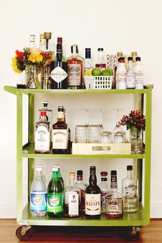 a shelf filled with bottles and glasses on top of a wooden floor