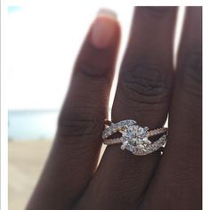 a woman's hand with a diamond ring on top of her finger and the other hand holding an engagement ring