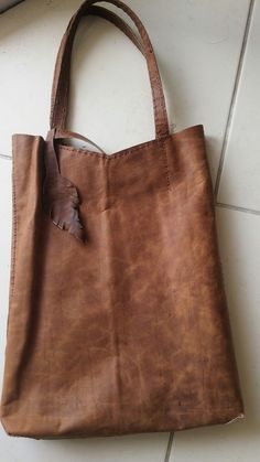 a brown leather tote bag sitting on top of a white tile floor