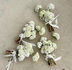 small bouquets of white flowers with ribbons tied around them sitting on the cement floor