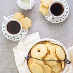 two cups of coffee and some cookies on a table