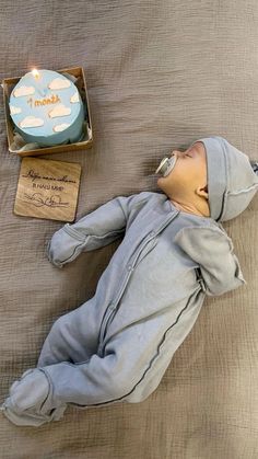 a baby doll laying on top of a bed next to a box with a candle