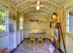 the inside of a building with two yellow stools in front of a painting easel