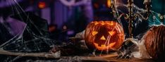 a carved jack - o'- lantern sits on a table with spider webs