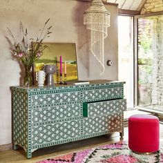 a room with a dresser, mirror and pink stool