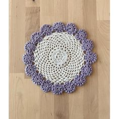 a purple and white crocheted doily on a wooden floor