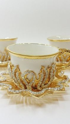 three white cups with gold trimmings on them