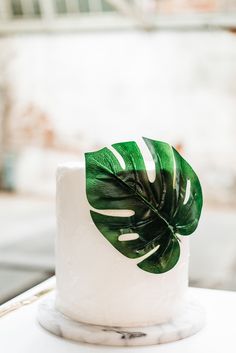 a white cake with a green leaf decoration on top