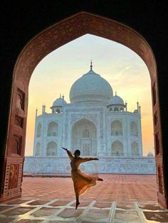 a woman is dancing in front of the tajwa mosque at sunset, india