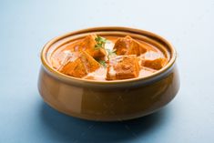 a brown bowl filled with food on top of a blue table