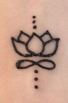 a lotus tattoo on the back of a woman's stomach, with black dots around it