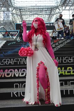 a woman dressed in pink and white is standing on some stairs with her hands up