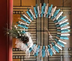 a wreath made out of clothes pegs is hanging on the front door with a pine cone