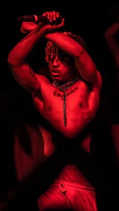 a shirtless man holding a microphone up to his head while standing in the dark