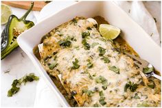 a white casserole dish filled with green vegetables and topped with cheese, cilantro