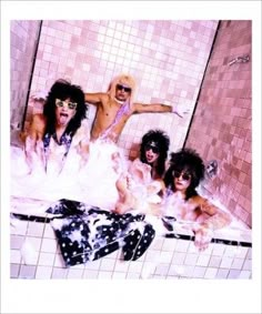 four people in a bathtub with pink tiles