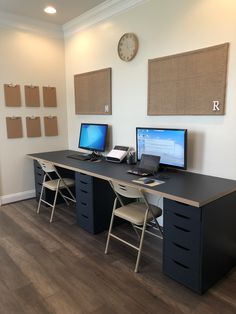 there are two computers on the desk in this office space, one is turned on