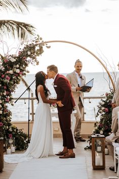 a bride and groom are getting married under an arch at the beach wedding ceremony in front of the ocean