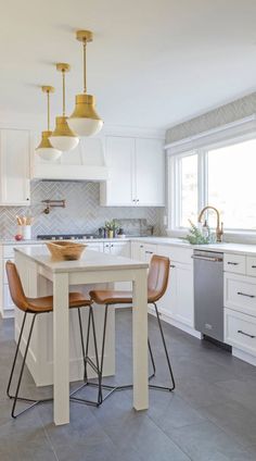 a kitchen with white cabinets and stainless steel appliances, including a marble counter top island