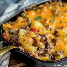 a casserole dish with meat, cheese and vegetables in it on a wooden table