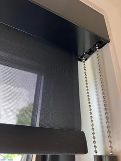 a close up of a window with a chain hanging from it's curtain rod