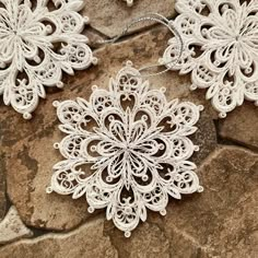 two white snowflakes sitting on top of a stone floor next to each other