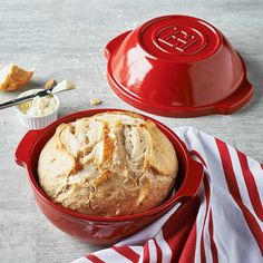 a loaf of bread sitting in a red bowl on top of a white and red towel