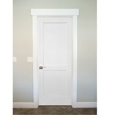 an empty room with a white door and carpeted floor in front of the wall