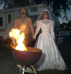 a bride and groom standing next to a fire pit