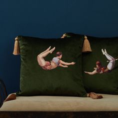 two decorative pillows on a bed with tassels