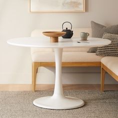 a white table in a living room with a couch and coffee pot on the table